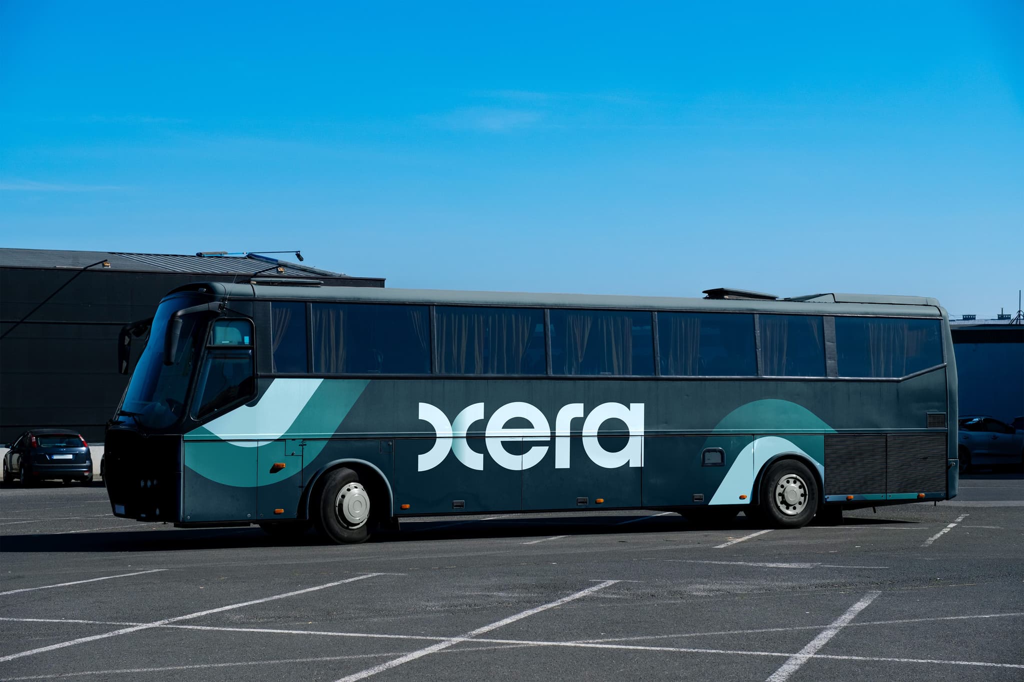 Coach bus mockup featuring a sleek design with the "Xcera" branding against a clear blue sky.