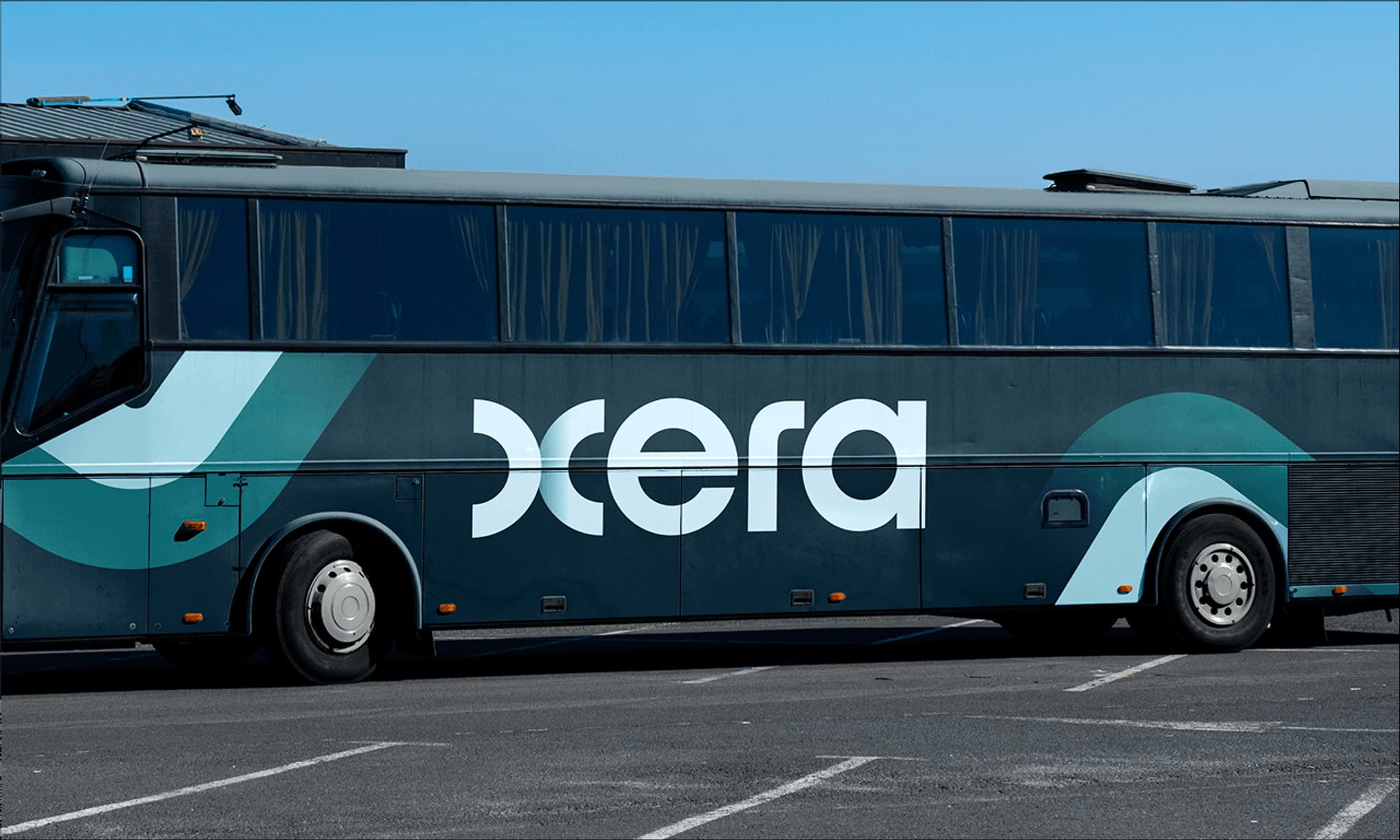 Green and white bus with "xera" branding, parked in a lot against a clear blue sky.