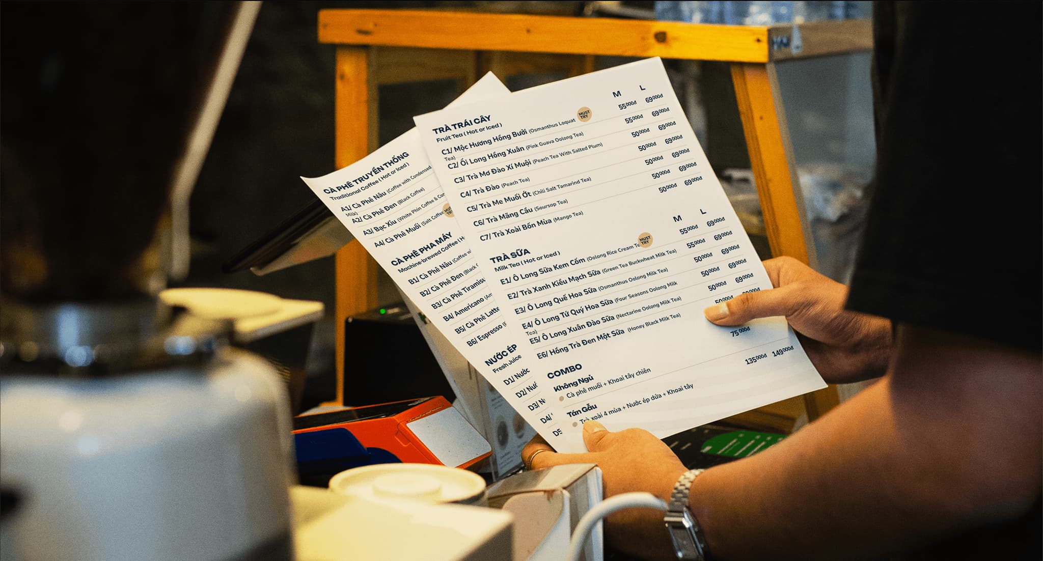 Cafe menu mockup held by a person, featuring various food and drink items with prices.