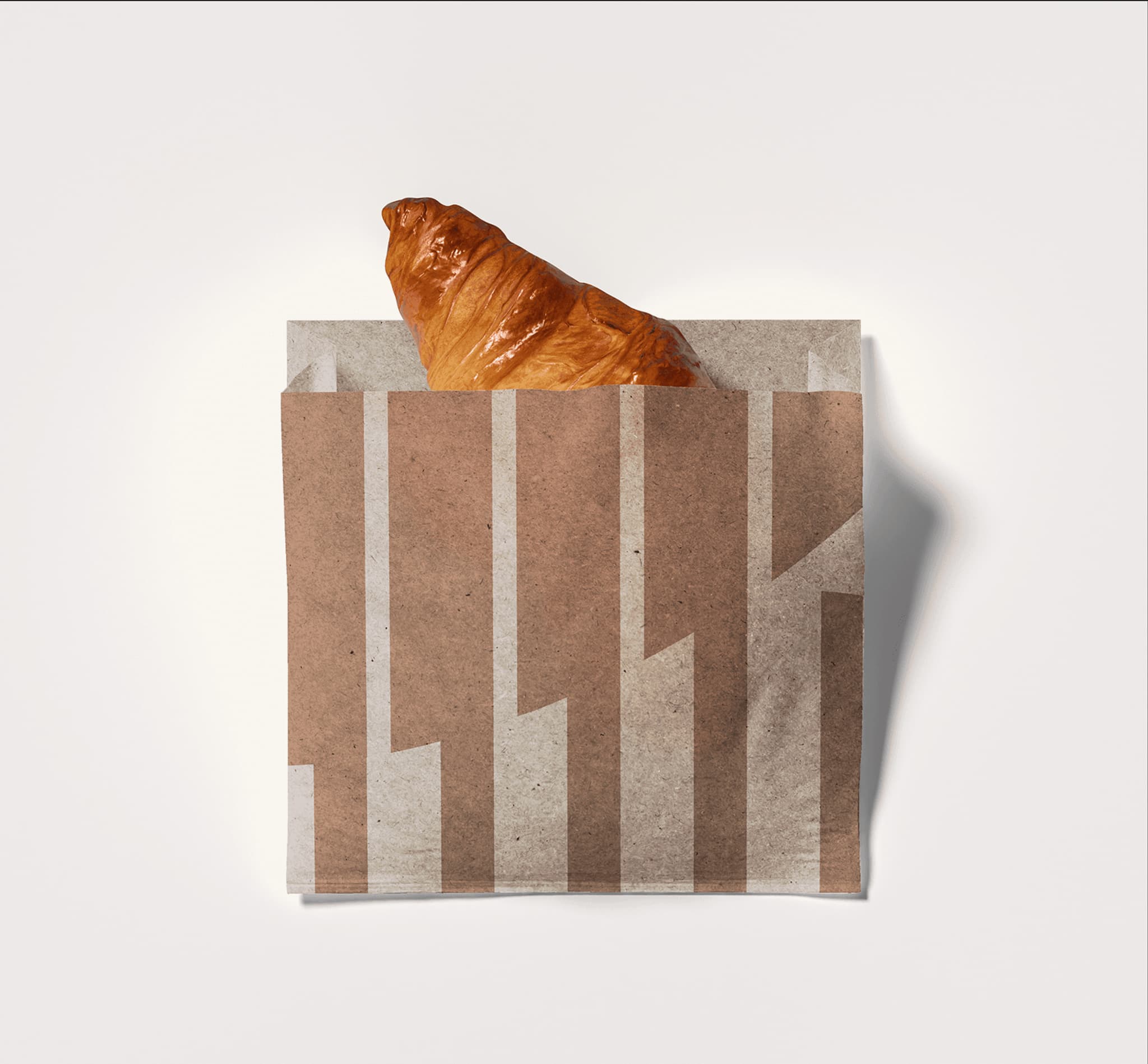 Brown paper bag with a croissant peeking out, featuring a modern geometric design. Ideal for bakery or cafe branding.
