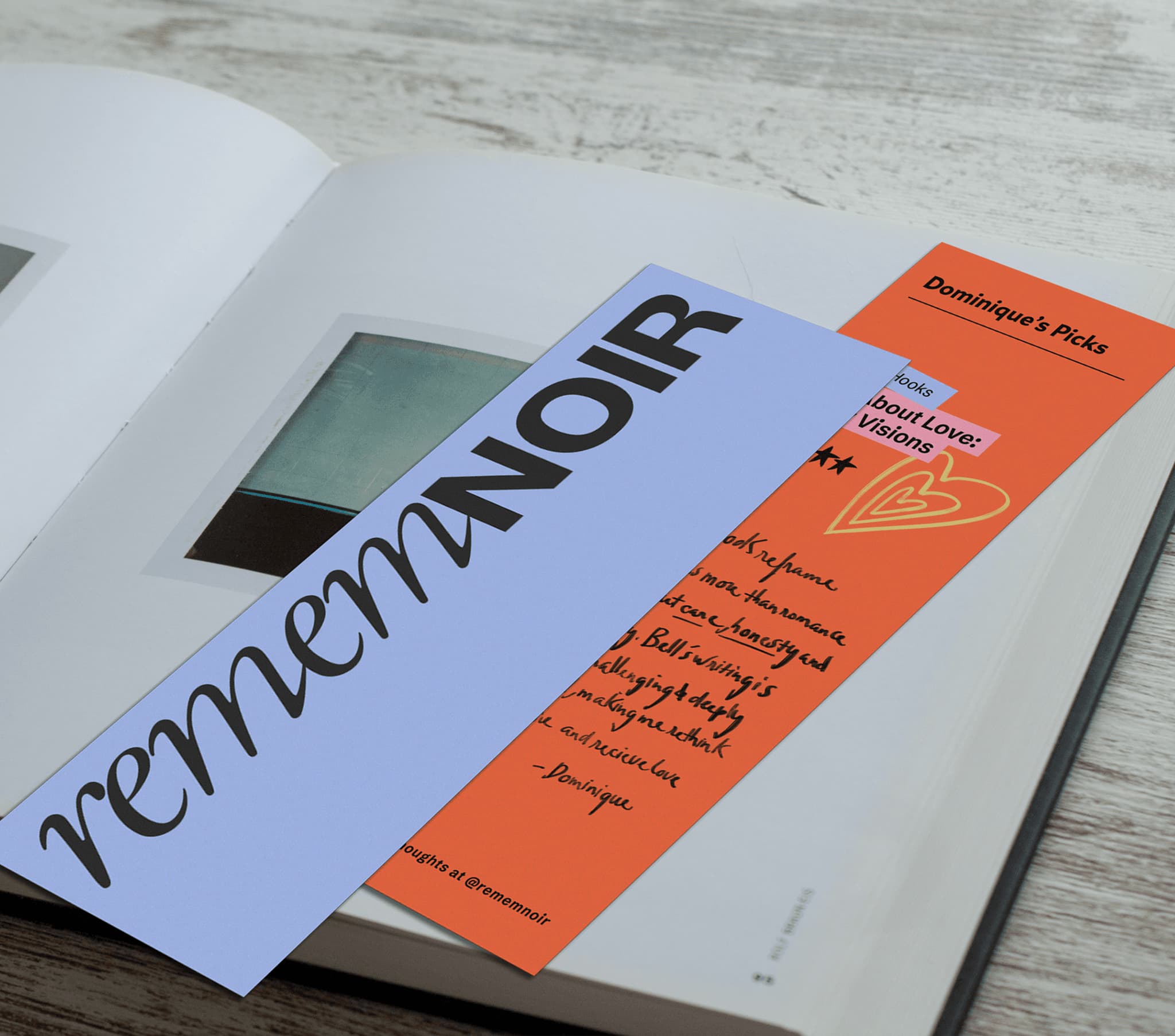 Bookmark titled "rememNOIR" on an open book, alongside an orange card with handwritten notes. Perfect for readers and book lovers.