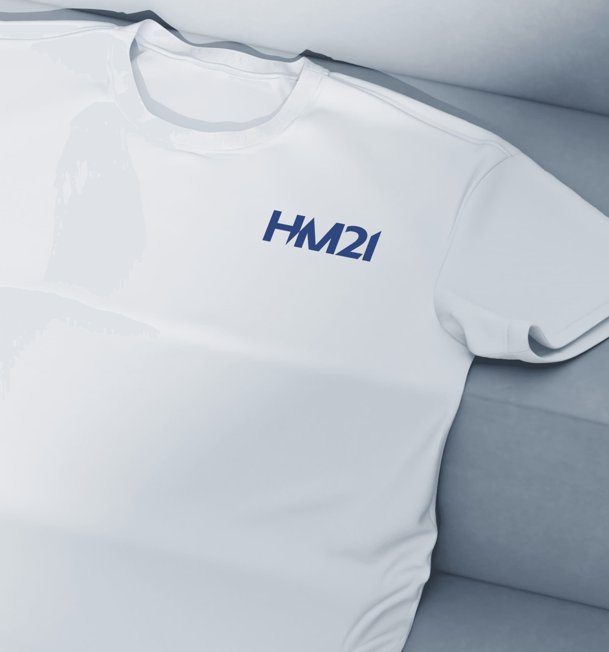 White T-shirt featuring a blue HM21 logo, laid flat on a soft surface. Perfect for casual wear and branding.