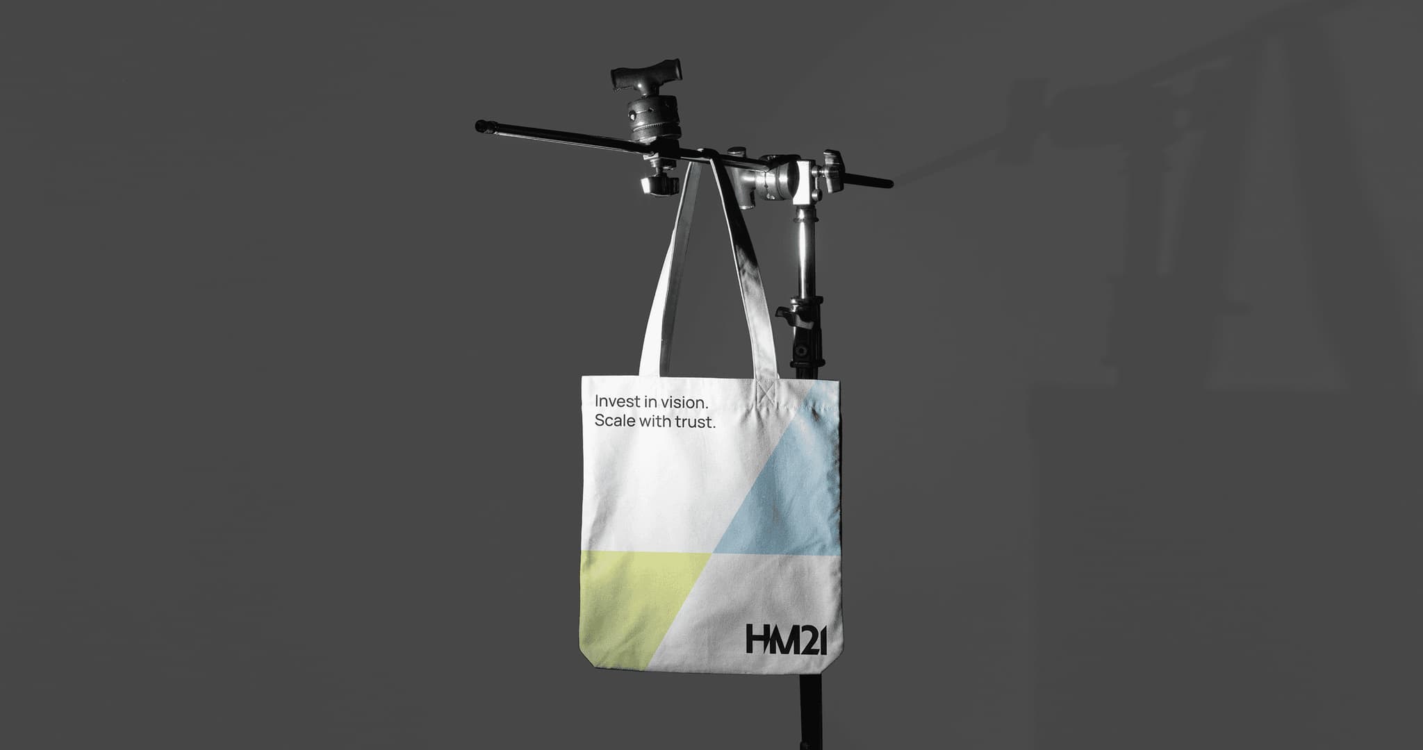 Tote bag hanging from a display, featuring a modern design with geometric shapes in blue and green.