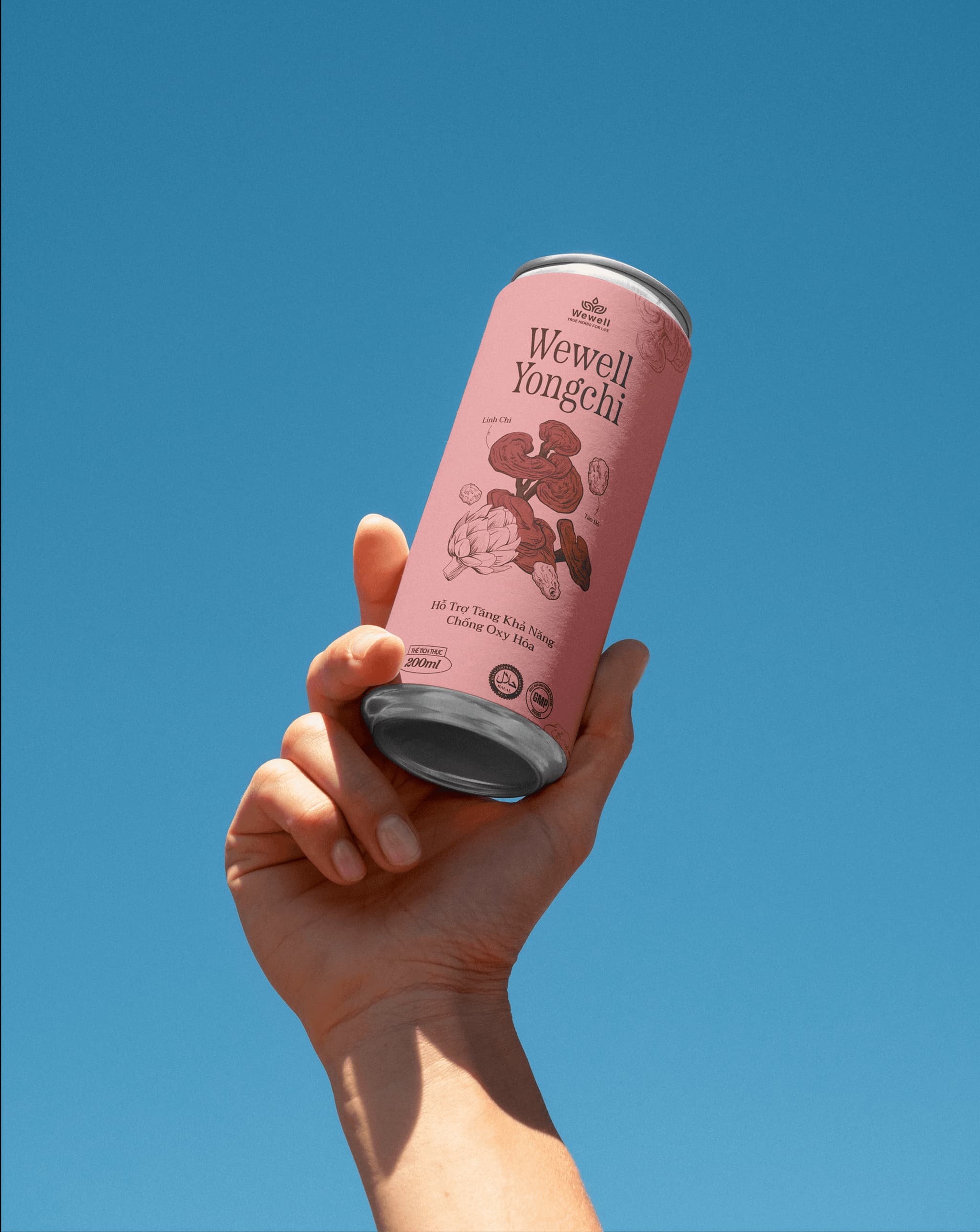 Hand holding a pink can of WeWell Yongchi, set against a clear blue sky. Refreshing tea beverage packaging design.